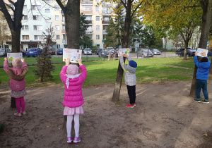 Dzieci instalują w ogrodzie plakaty ekologiczne.