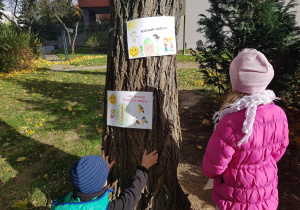 Dzieci instalują w ogrodzie plakaty ekologiczne.