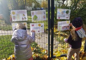 Dzieci instalują w ogrodzie plakaty ekologiczne.