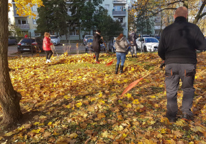 Dzieci grabią liście w ogrodzie.