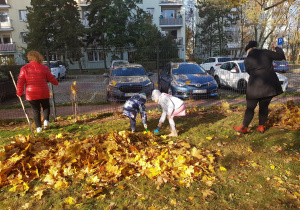 Dzieci grabią liście w ogrodzie.