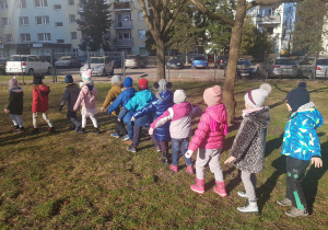 Dzieci uczestniczą w zabawach ruchowych w ogrodzie.