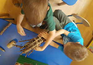 Dzieci związują patyki i tworząc domki dla owadów.
