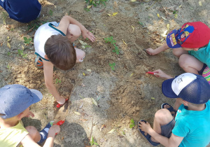 Dzieci bawią się w piaskownicy - odkopują poukrywane na stanowisku geologicznymelementy.