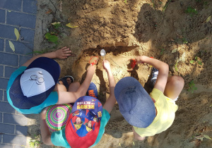 Dzieci bawią się w piaskownicy - odkopują poukrywane na stanowisku geologicznymelementy.