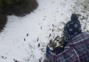 Dzieci oglądają tropy ptaków na śniegu.