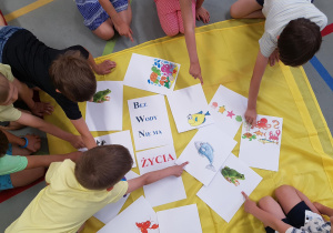 Dzieci przygotowują kolorowe ulotki na temat oszczędzania wody.