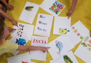 Dzieci przygotowują kolorowe ulotki na temat oszczędzania wody.