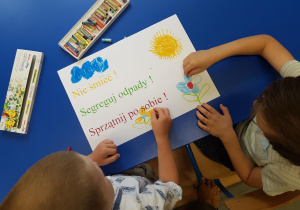 Dzieci przygotowują plakaty na temat ochrony przyrody.