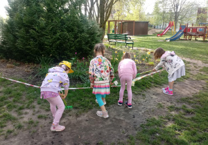 Dzieci grabią trawę w ogrodzie.