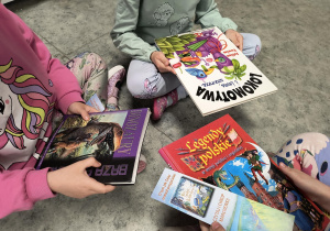 Dzieci przy regale i oglądają książki w bibliotece szkolnej.