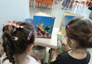 Dzieci oglądają książki w bibliotece szkolnej.