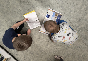 Dzieci siedzą i oglądają książki w bibliotece szkolnej.