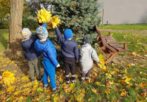 Grupa czterech chłopców trzyma w ręku bukiety z liści.