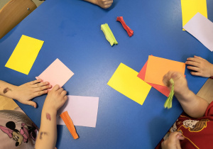 Dzieci wykonują rybki z kolorowego papieru.