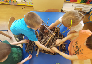 Dzieci ukłądają patyki i tworząc domki dla owadów.