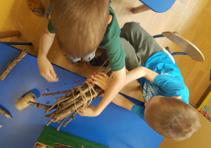 Dzieci związują patyki i tworząc domki dla owadów.