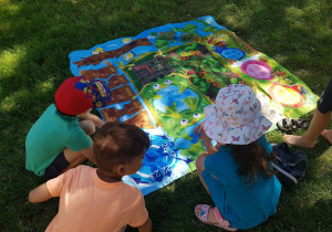 Dzieci w ogrodzie grają w grę edukacyjną.