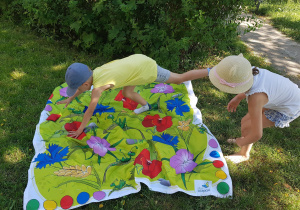 Dzieci w ogrodzie grają w grę edukacyjną.