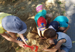 Dzieci bawią się w piaskownicy - odkopują poukrywane na stanowisku geologicznymelementy.