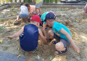 Dzieci bawią się w piaskownicy - odkopują poukrywane na stanowisku geologicznymelementy.