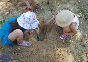 Dzieci bawią się w piaskownicy - odkopują poukrywane na stanowisku geologicznymelementy.