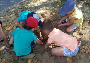 Dzieci bawią się w piaskownicy - odkopują poukrywane na stanowisku geologicznymelementy.