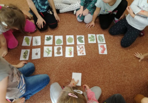 Dzieci siedzą na dywanie i układają obrazki.