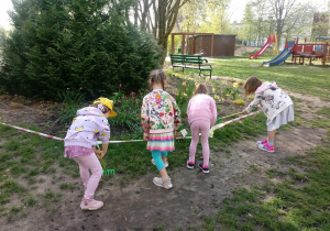 Dzieci grabią trawę w ogrodzie.